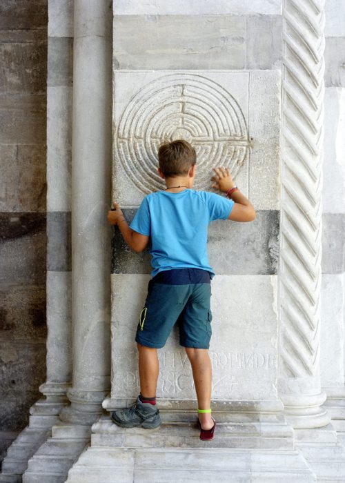 Passage de Petit homme de Leandro, Langres - Rome 1520 km à pied. Étape 42 Ville de Lucques. Labyrinthe gravé sur un pilier du portique de la cathédrale Saint-Martin de Lucques. Leandro n'a qu'une chaussure de marche car après plus de 1000 km, sa chaussure est complètement cassé et ne tient plus son pied. Quand le cordonnier italien a vu l'etat de la chaussure et qu'il a su ce que Leandro faisait, il le lui a réparer et lui a offert la réparation pour son courage!